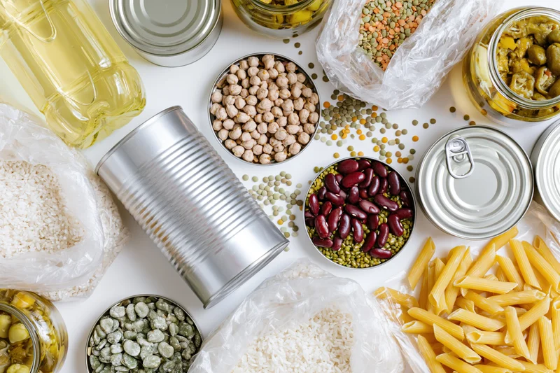 Overhead flat-lay of pantry staples and emergency food supplies arranged on white surface