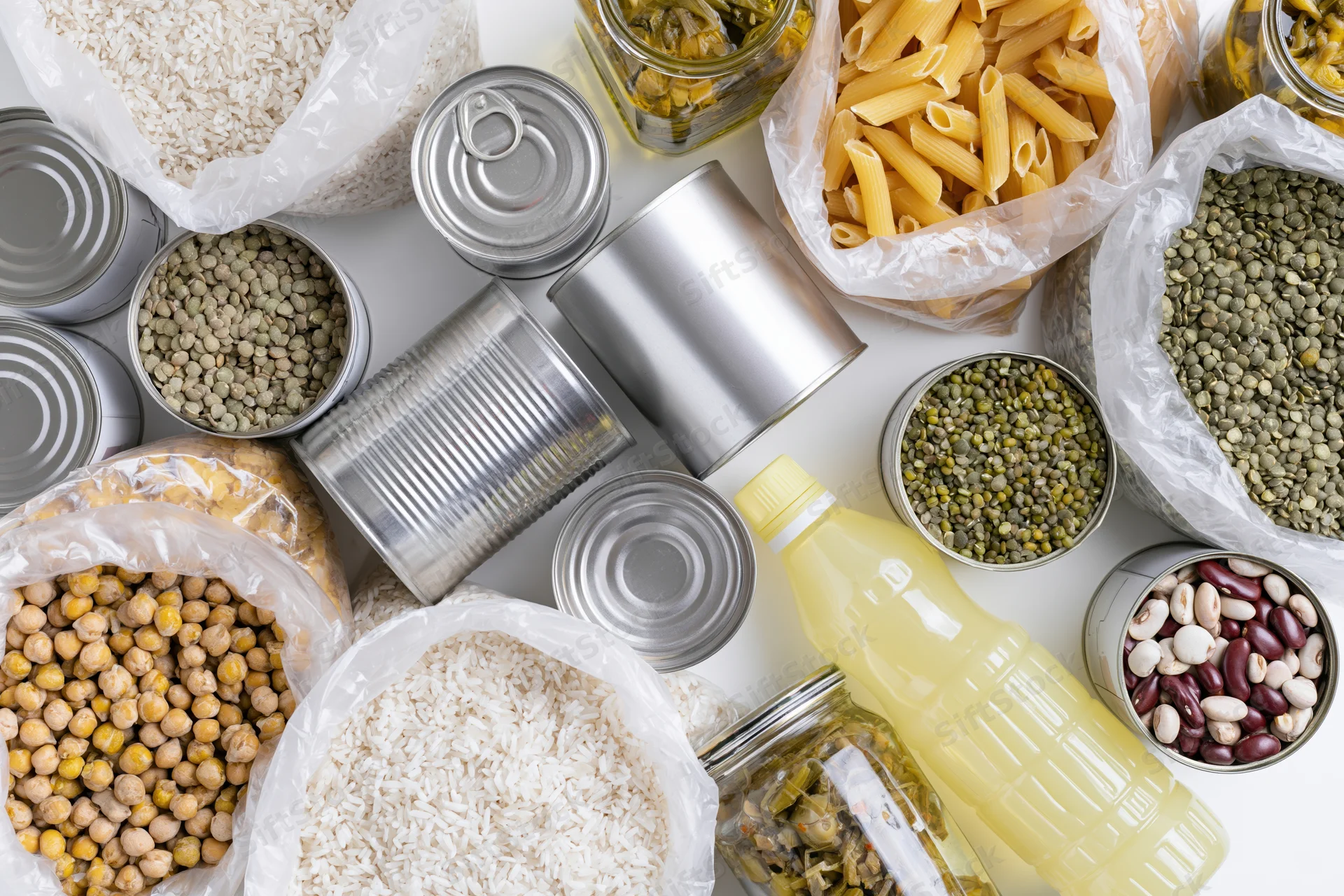 Overhead flat-lay of pantry staples and emergency food supplies arranged on white surface