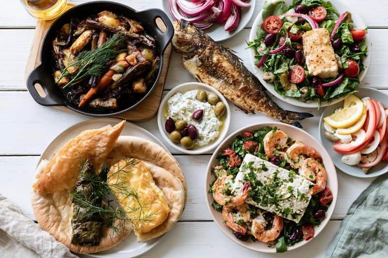 Greek mezze spread with grilled fish, salads, pita, and dips on white wooden table