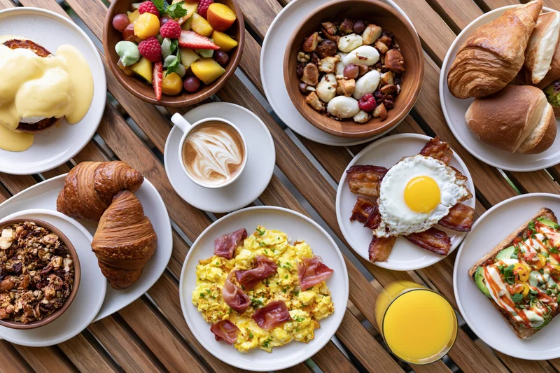 Overhead view of a full brunch spread with various dishes and drinks arranged on a slatted wooden table