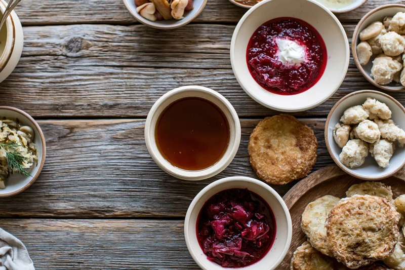 Rustic eastern european meal spread on wooden table with bowls of compote, honey, dumplings and biscuits