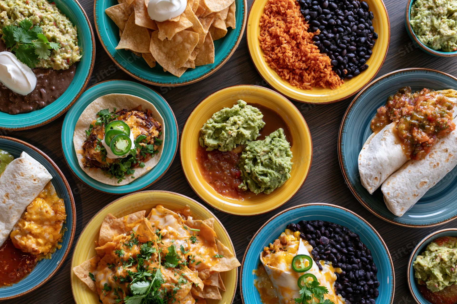 Overhead flat lay of mexican dishes arranged on a dark wooden table