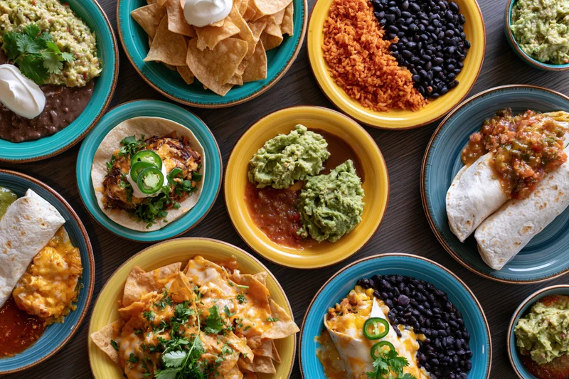 Overhead flat lay of mexican dishes arranged on a dark wooden table