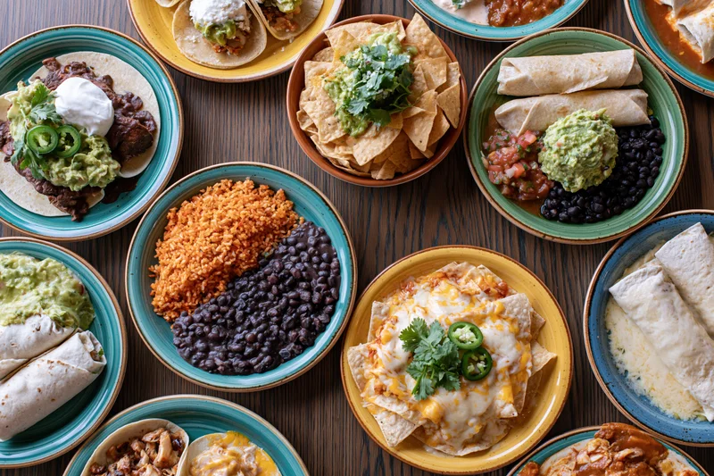Overhead flat lay of a spread of mexican dishes on a dark wooden table
