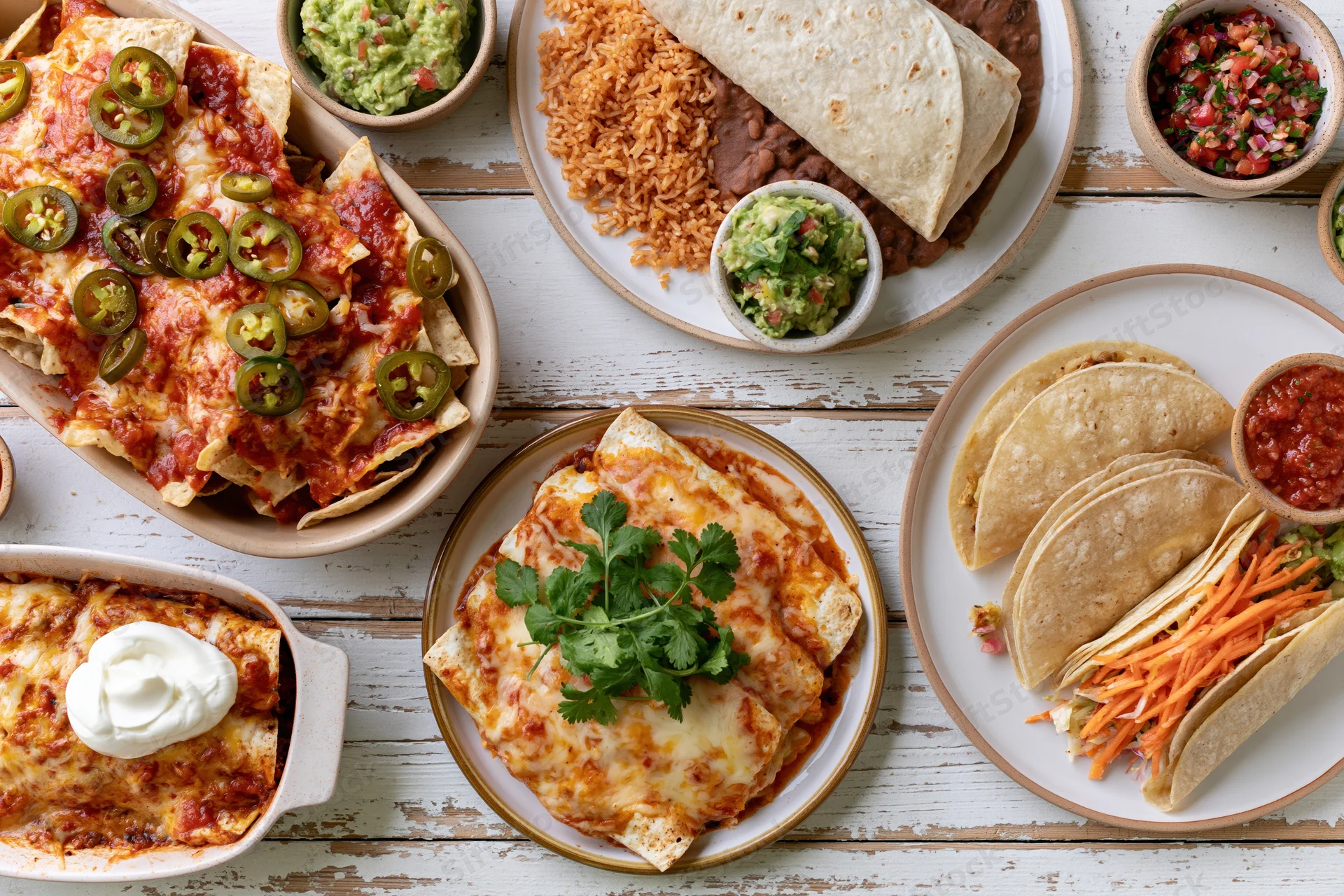 Overhead flat lay of mexican dishes arranged on a white wooden table