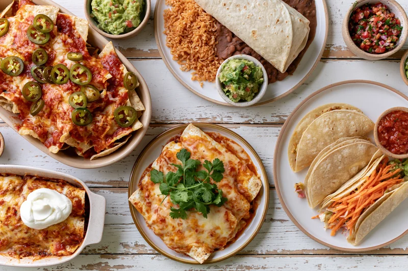 Overhead flat lay of mexican dishes arranged on a white wooden table