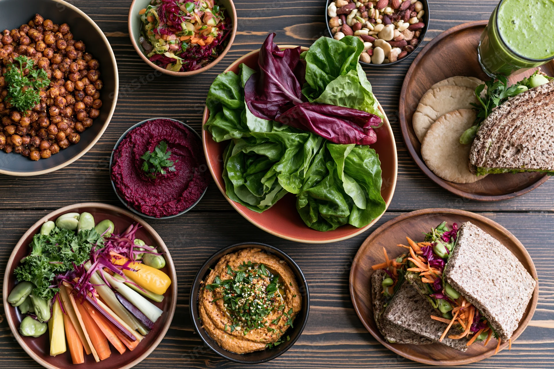 Overhead flat lay of a spread of healthy vegetarian dishes on a dark wooden table