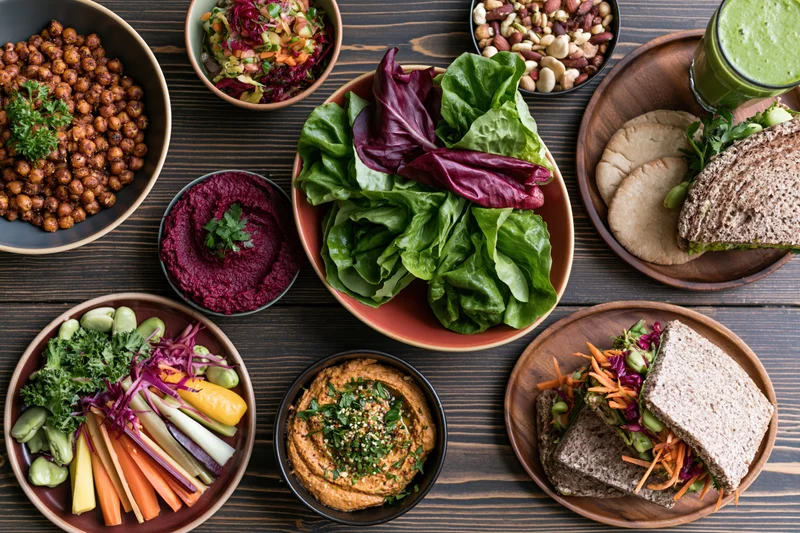 Overhead flat lay of a spread of healthy vegetarian dishes on a dark wooden table