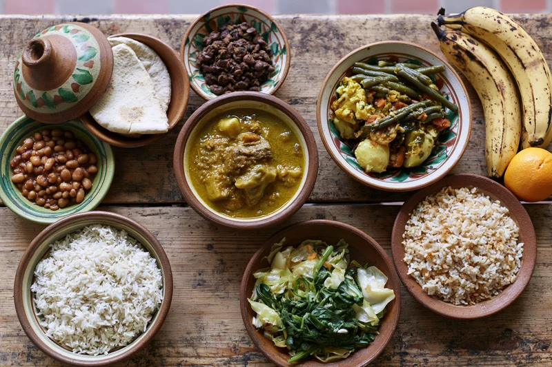 Traditional african and caribbean dishes arranged in ceramic bowls on a wooden table