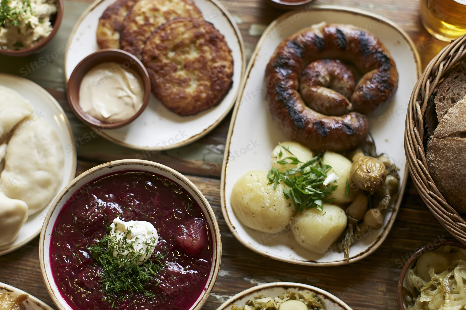Traditional eastern european meal spread with borscht, sausage, pierogi, and bread on wooden table