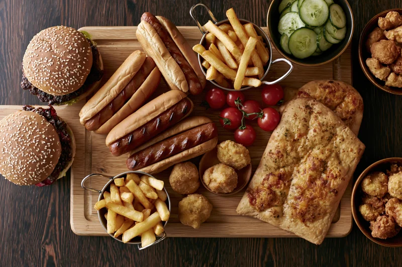 Overhead flat lay of assorted fast food items arranged on a wooden tray and table