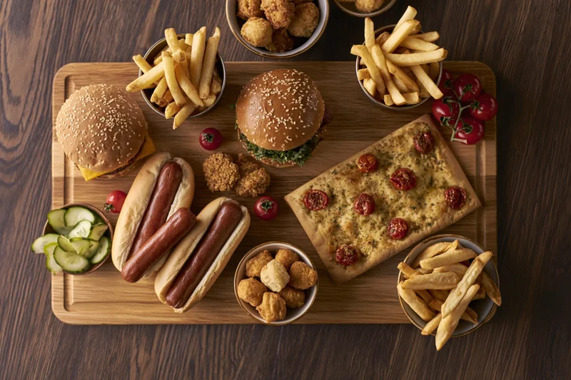 Overhead flat lay of assorted fast food items arranged on a wooden tray