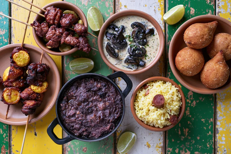 Assorted brazilian dishes arranged on a rustic wooden table in overhead flat lay view