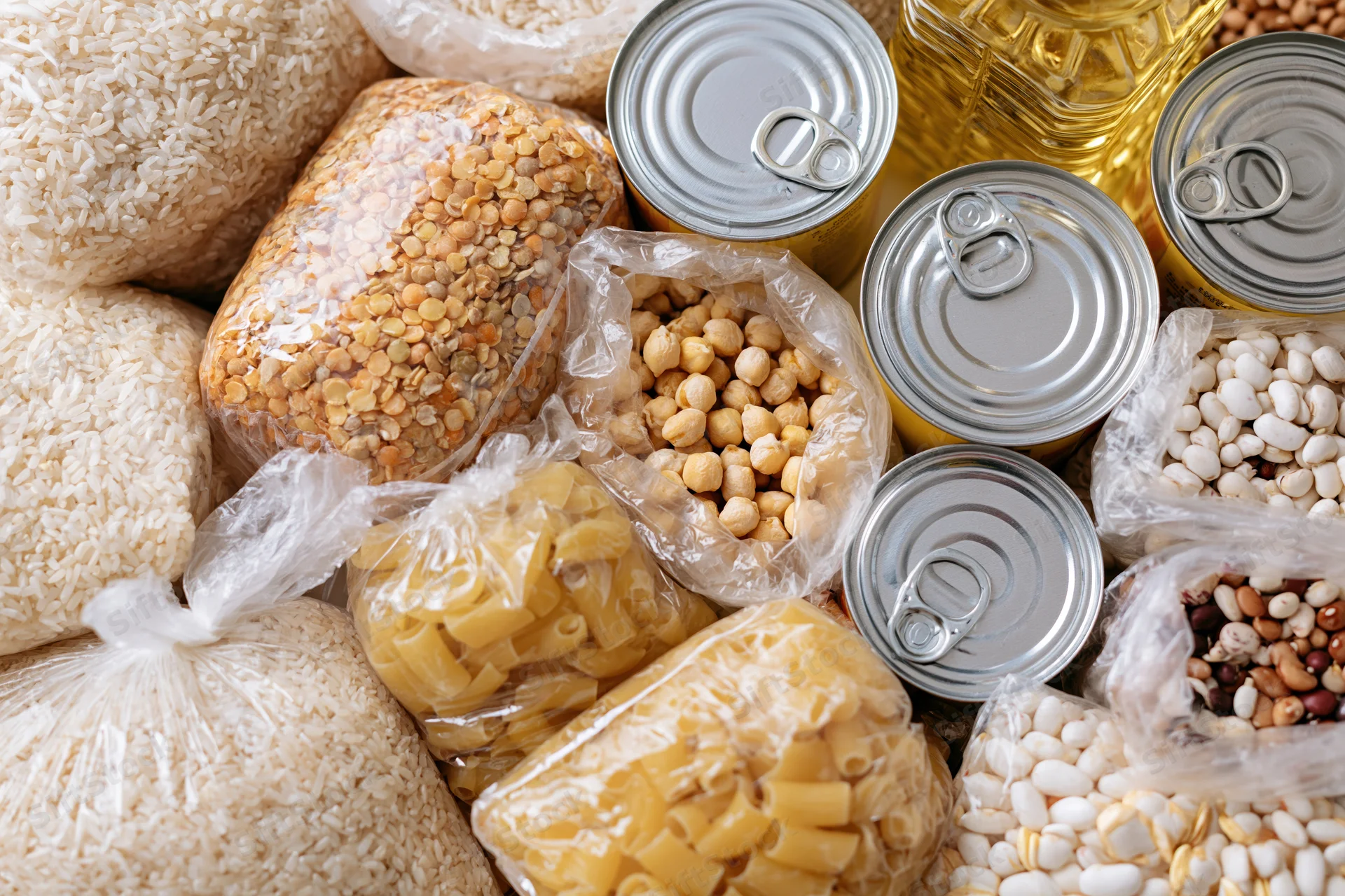 Overhead flat lay of assorted dry pantry staples and canned goods arranged together