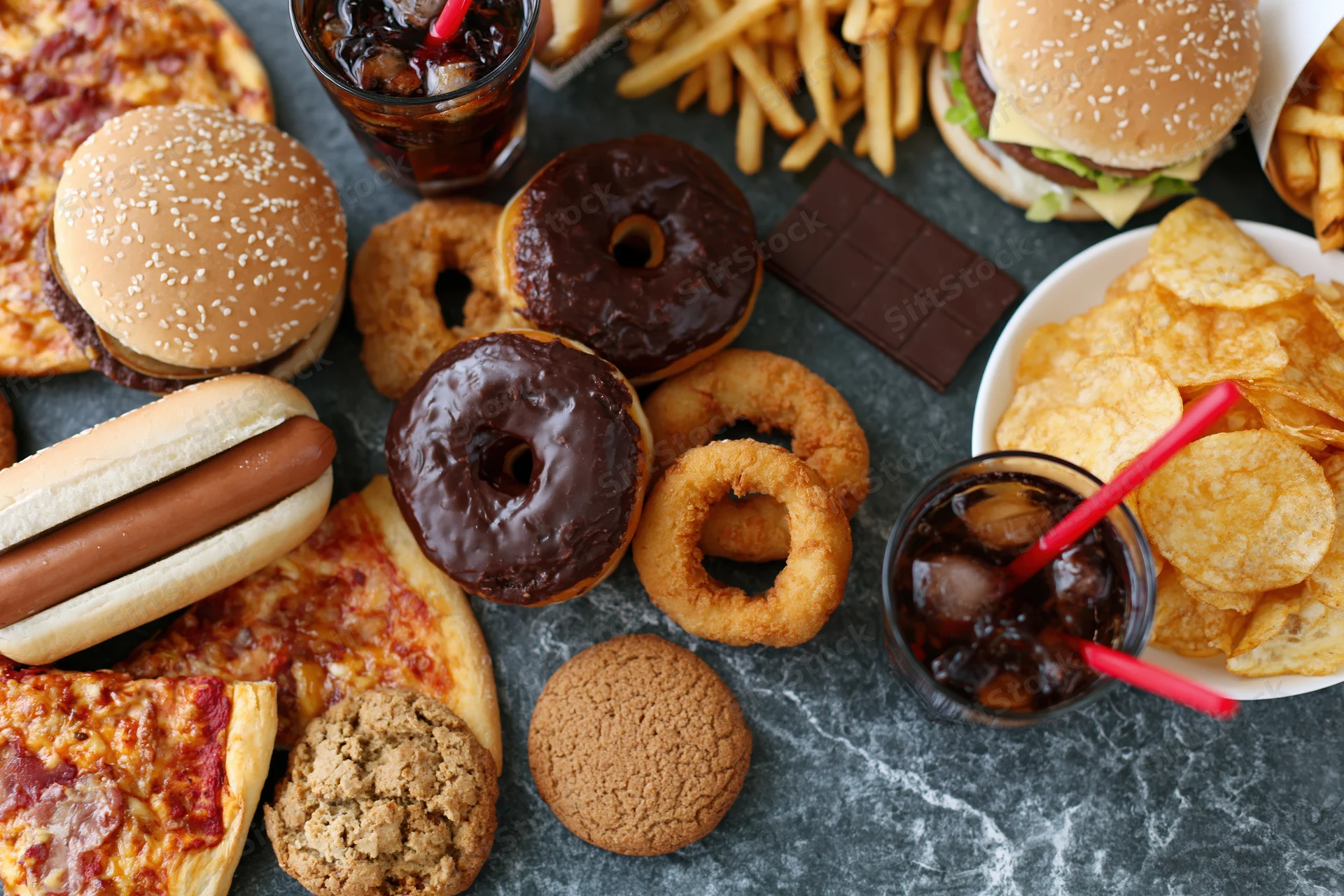 Overhead flat lay of assorted fast food and junk food spread on gray marble surface
