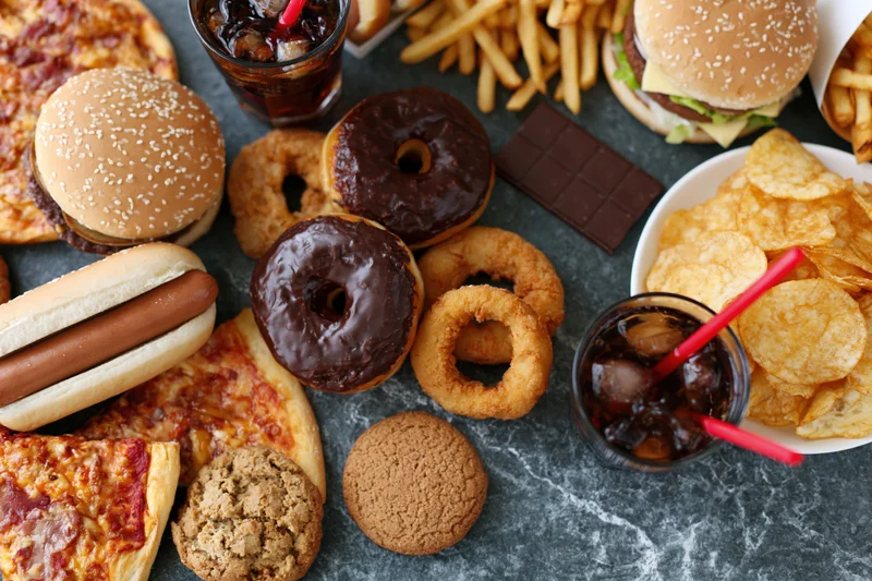 Overhead flat lay of assorted fast food and junk food spread on gray marble surface