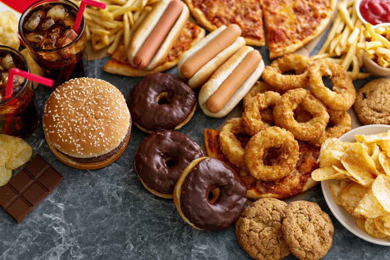 Overhead flat lay of assorted fast food and junk food spread on dark surface