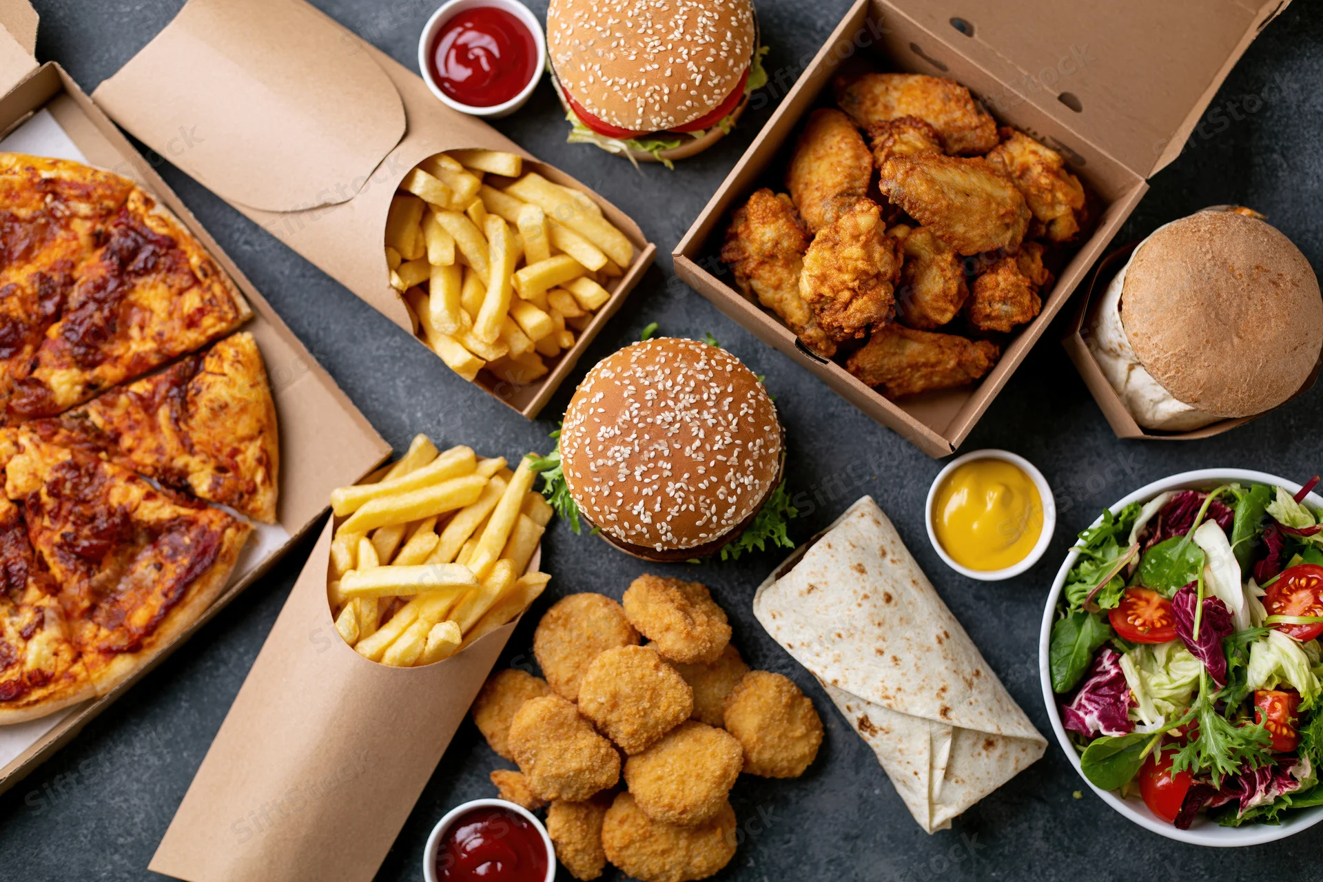 Assorted fast food items arranged in a flat lay on a dark surface