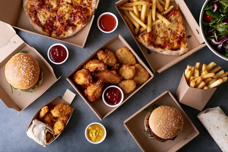Assorted fast food items arranged in open boxes on a dark surface