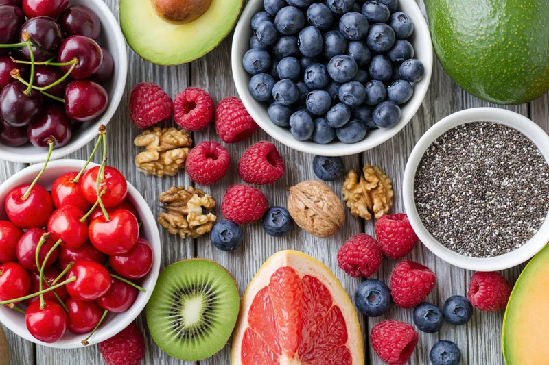 Overhead flat lay of fresh fruits berries nuts and chia seeds on wooden table