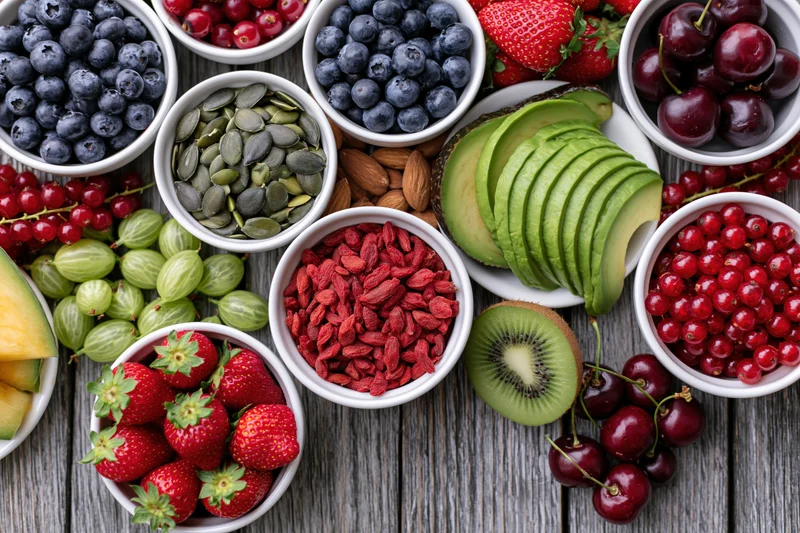 Overhead flat lay of assorted fresh fruits berries nuts and seeds on wooden table