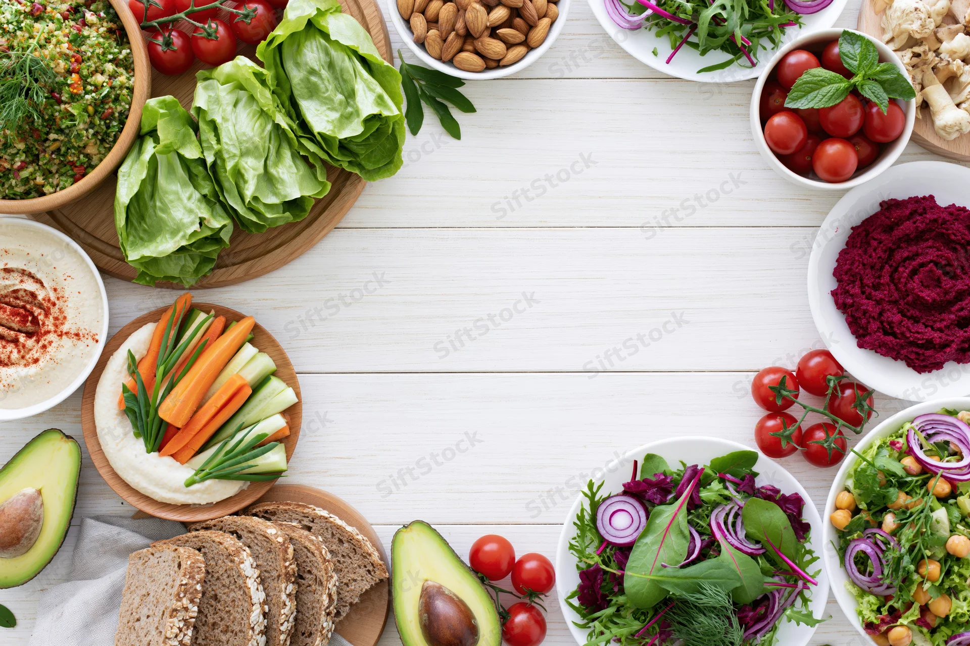 Overhead flat lay of assorted healthy vegetarian dishes and ingredients arranged on a white wooden table with copyspace