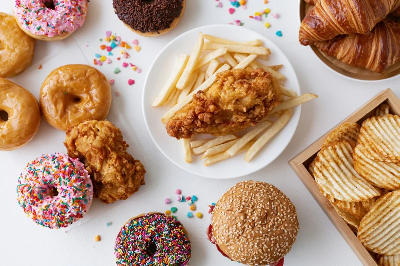 Assorted junk food arranged in a flat lay on a white surface
