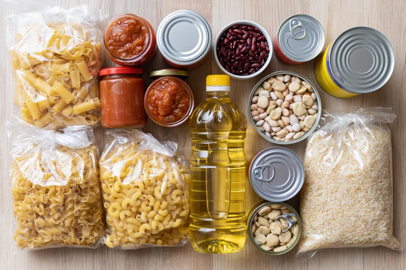 Assorted pantry staples arranged on a wooden surface in overhead flat lay view