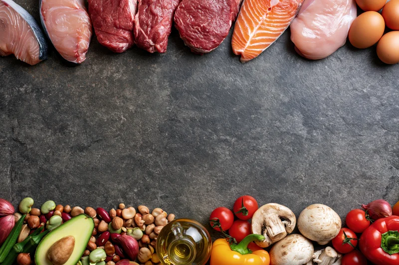 Assorted whole foods arranged as a border on dark slate surface with copyspace