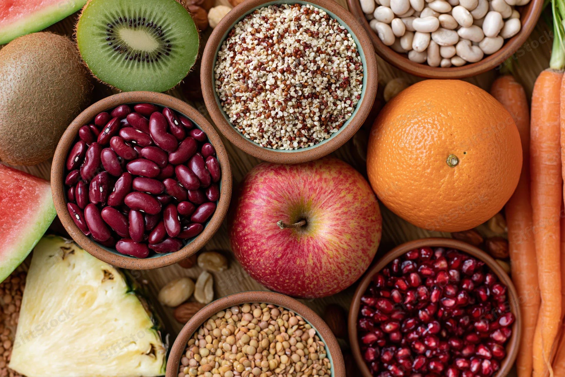 Overhead flat lay of assorted whole foods densely arranged on wooden surface