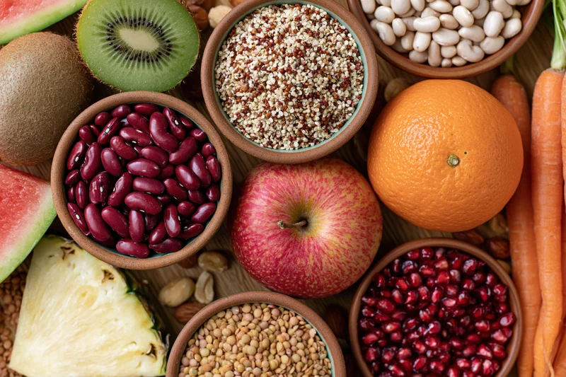 Overhead flat lay of assorted whole foods densely arranged on wooden surface