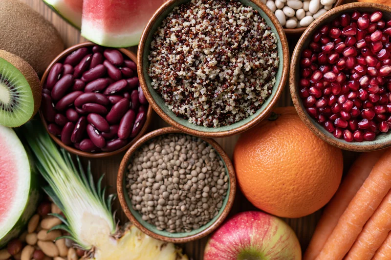 Overhead flat lay of assorted whole foods densely arranged on wooden surface