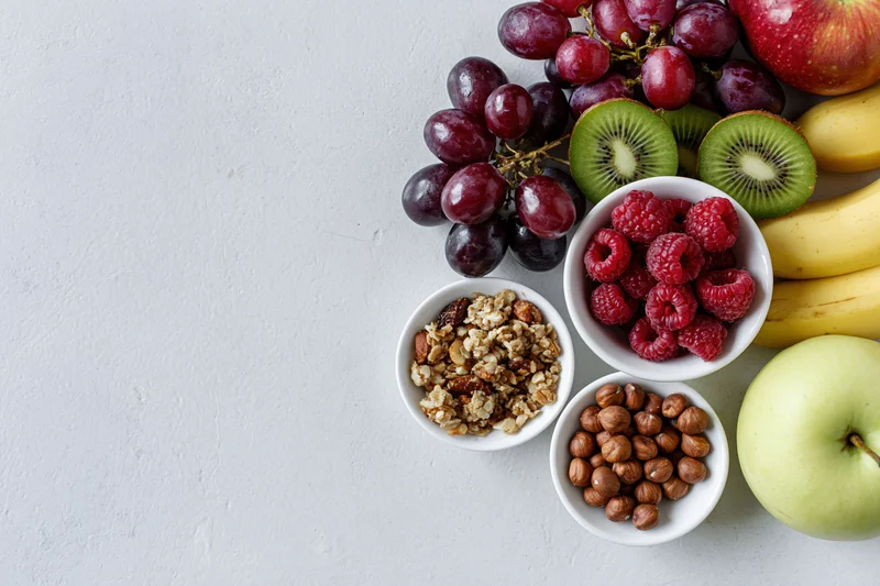 Overhead flat lay of breakfast ingredients arranged along the right side of a white surface with copyspace on the left