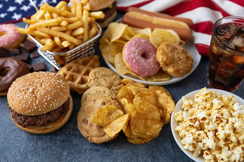 Overhead flat lay of classic american junk food spread across a table with flag in background