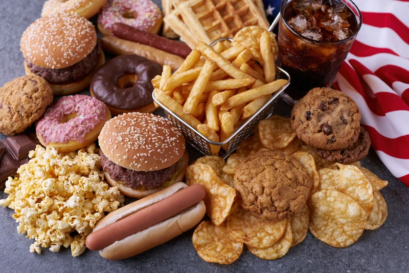 Overhead flat lay of classic american junk food spread across a table with flag and festive items