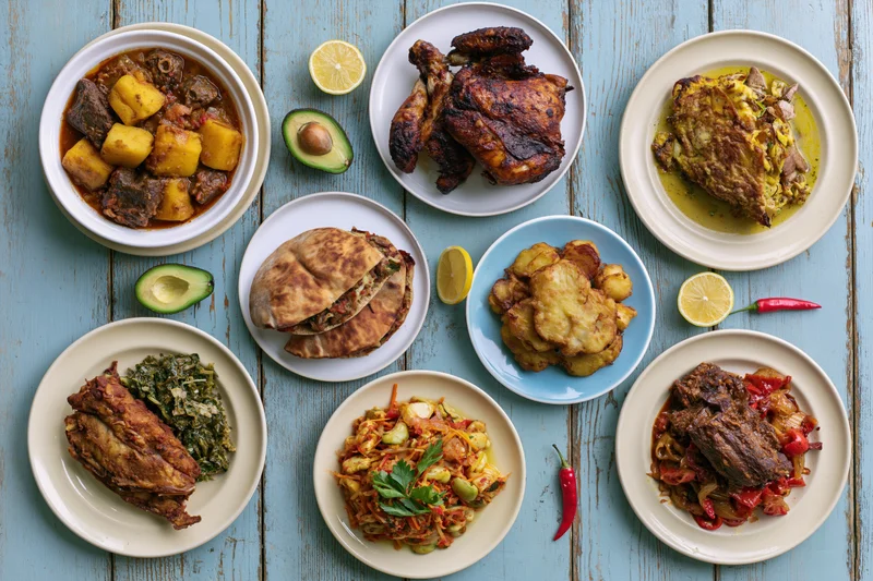 Eight dishes arranged on a blue wooden table in overhead flat lay view