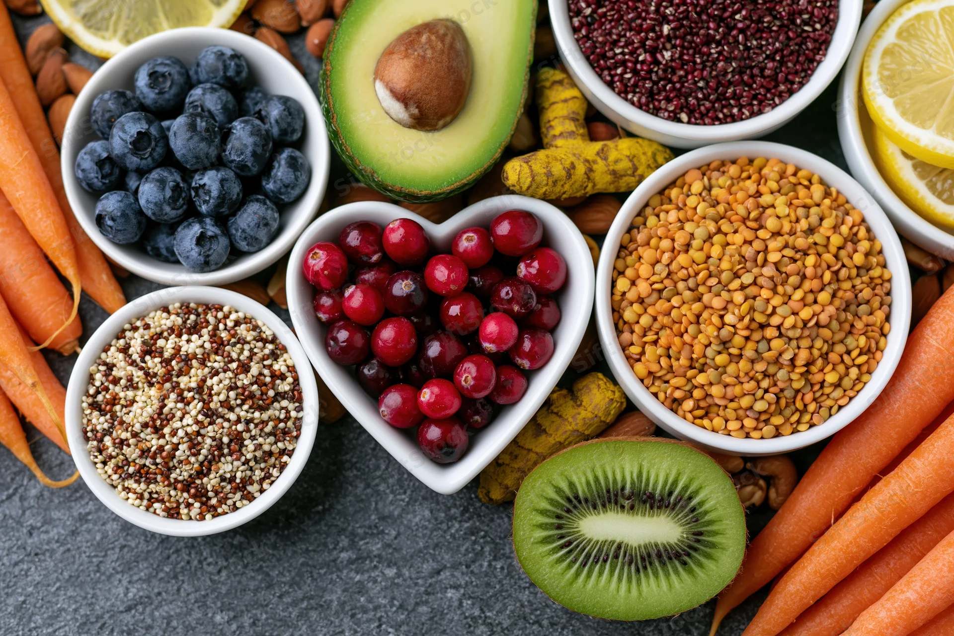Overhead flat lay of fresh fruits vegetables grains and nuts on gray surface