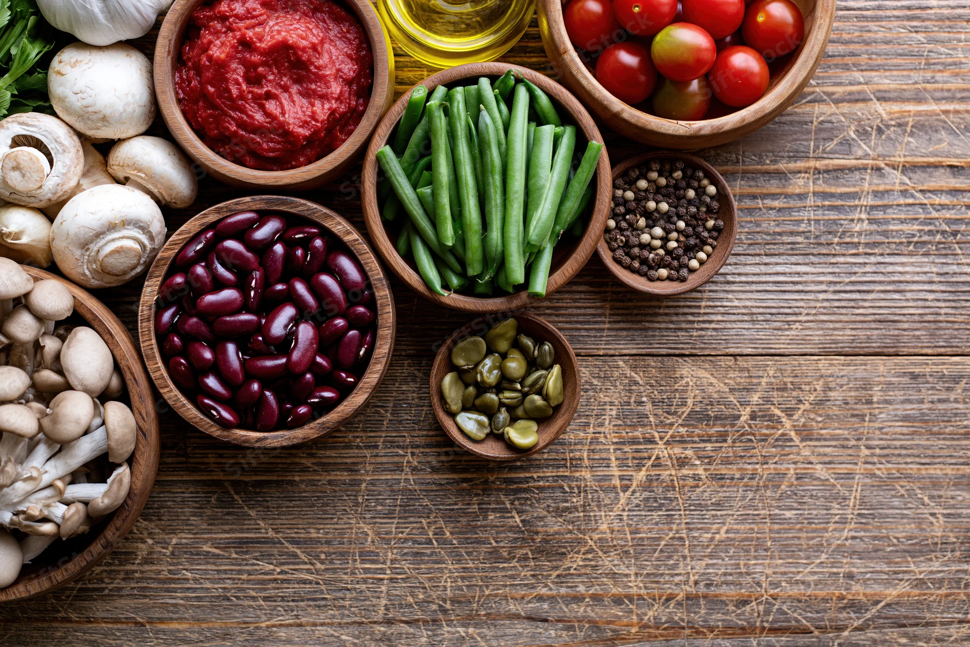 Overhead flat lay of fresh vegetables and pantry ingredients arranged on a wooden table