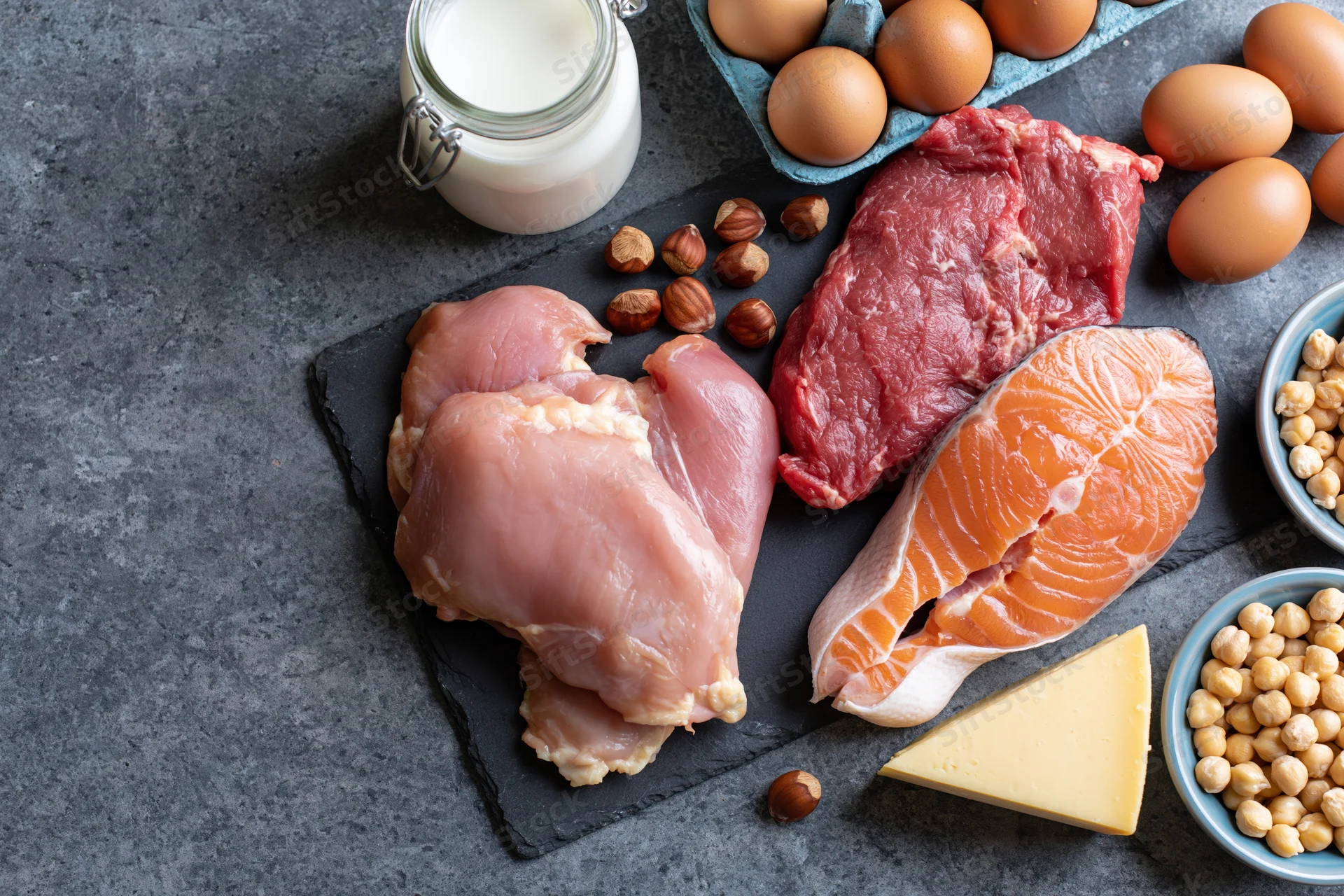 High-protein foods arranged on dark slate surface with copyspace on left