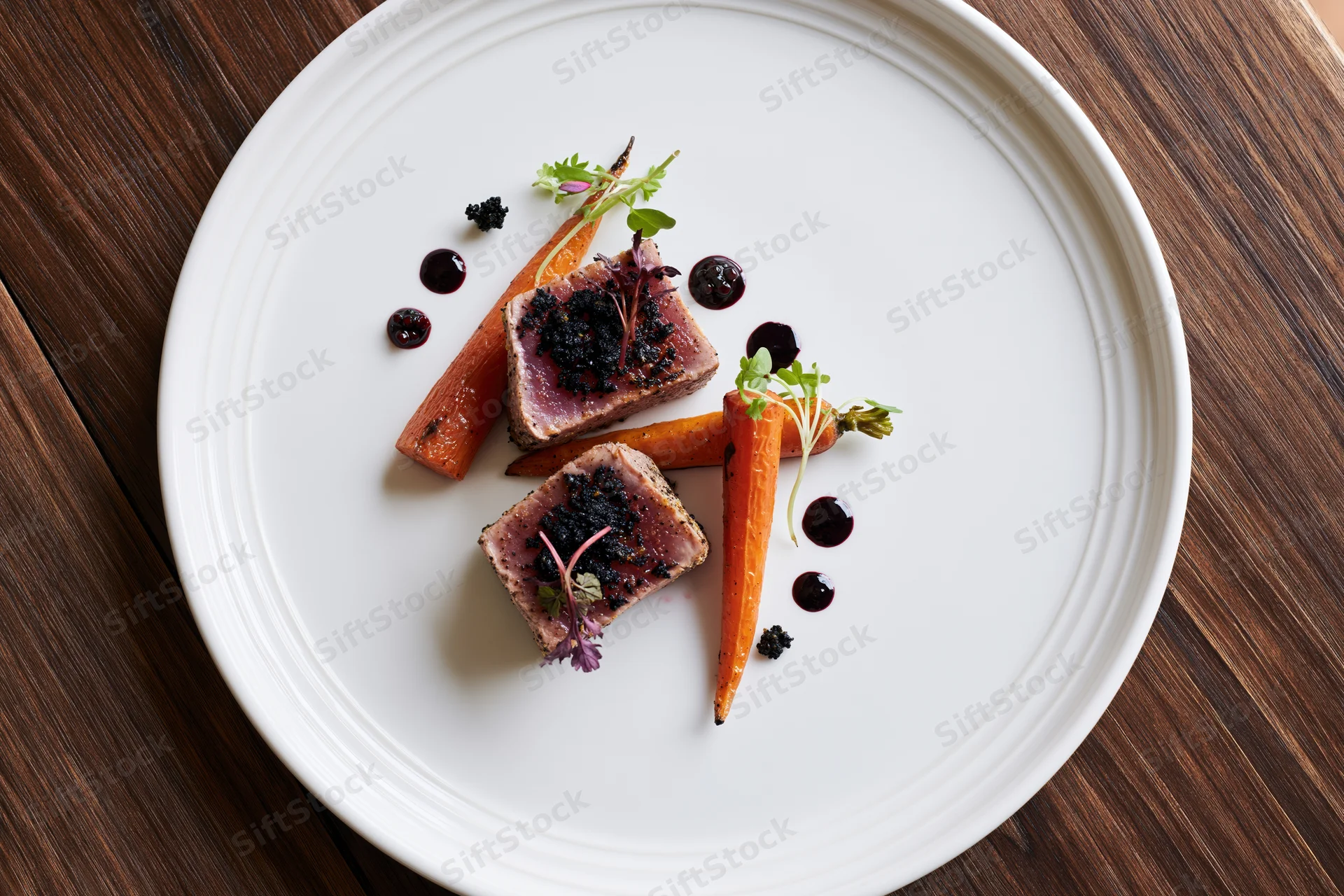 Two seared tuna medallions with carrots and garnish on a white plate on a wooden table