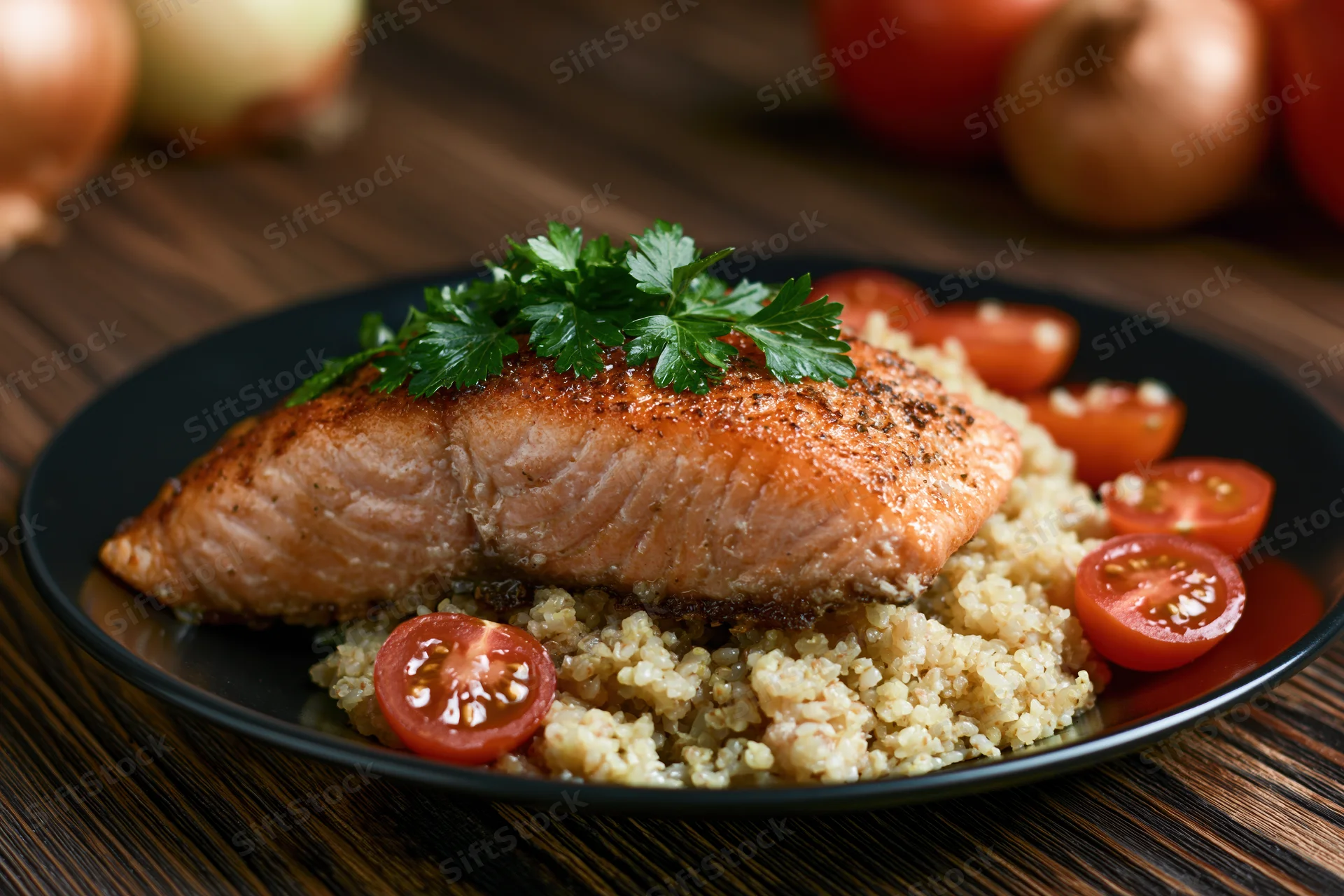 Pan-seared salmon fillet on a bed of quinoa with cherry tomatoes and parsley garnish on a wooden table