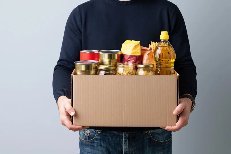 Man holding a cardboard box filled with nonperishable food items