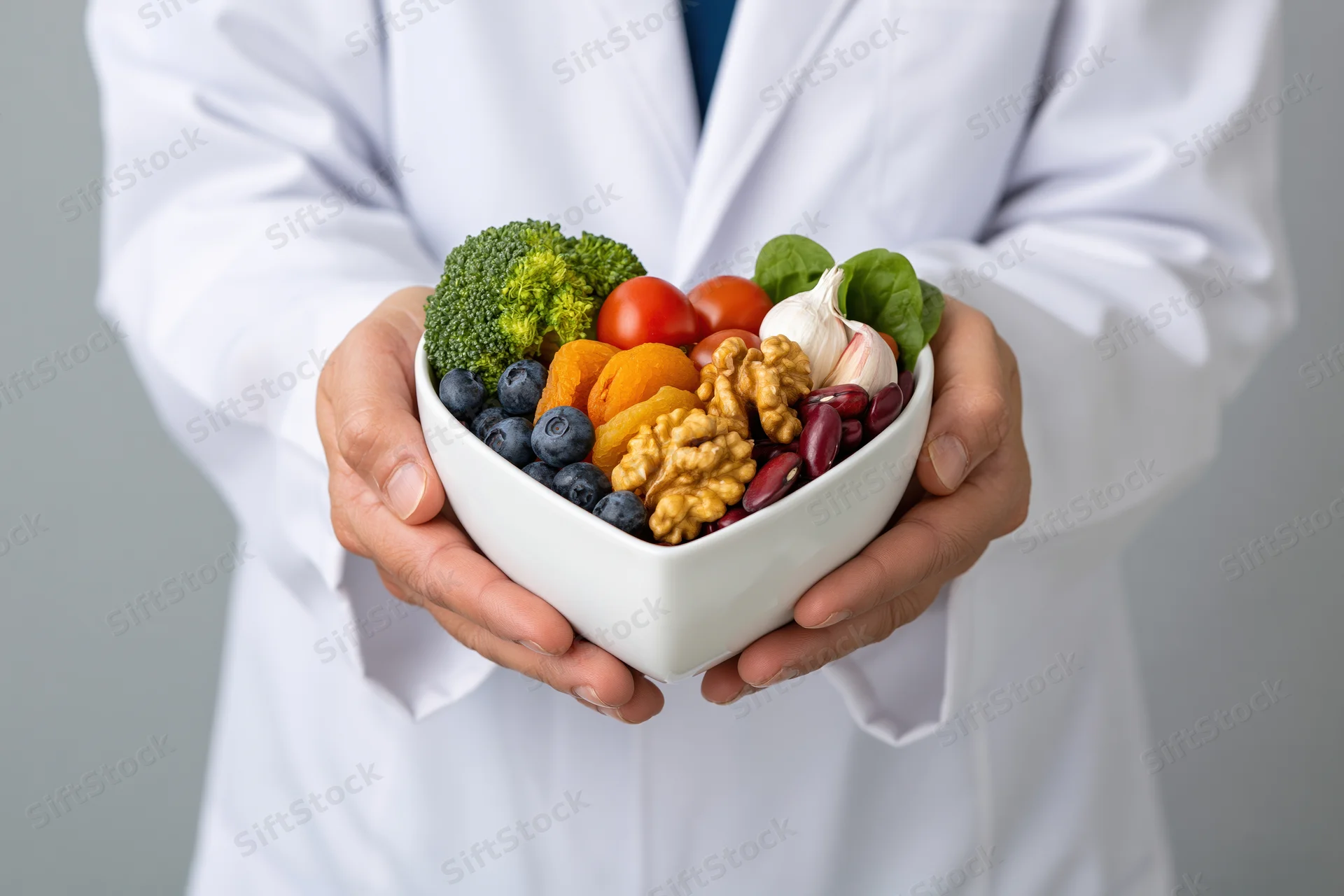 Dietitian holding heart-shaped bowl of colorful fruits vegetables and nuts in white lab coat