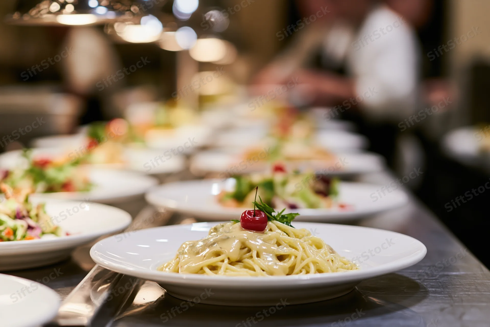 Pasta dish with creamy sauce and cherry garnish on white plate at restaurant buffet