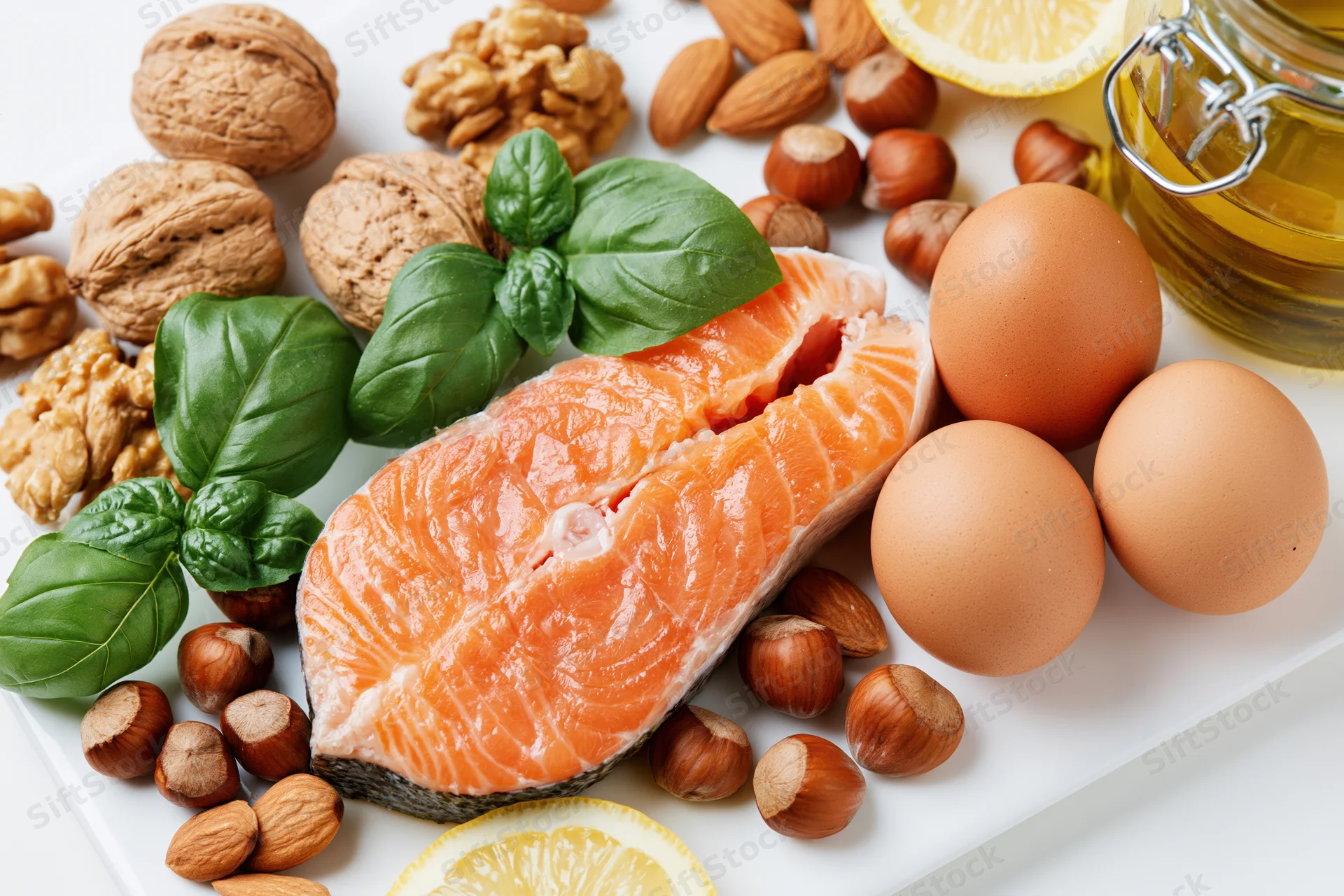 Raw salmon steak with eggs, nuts, basil, lemon, and olive oil arranged on a white plate