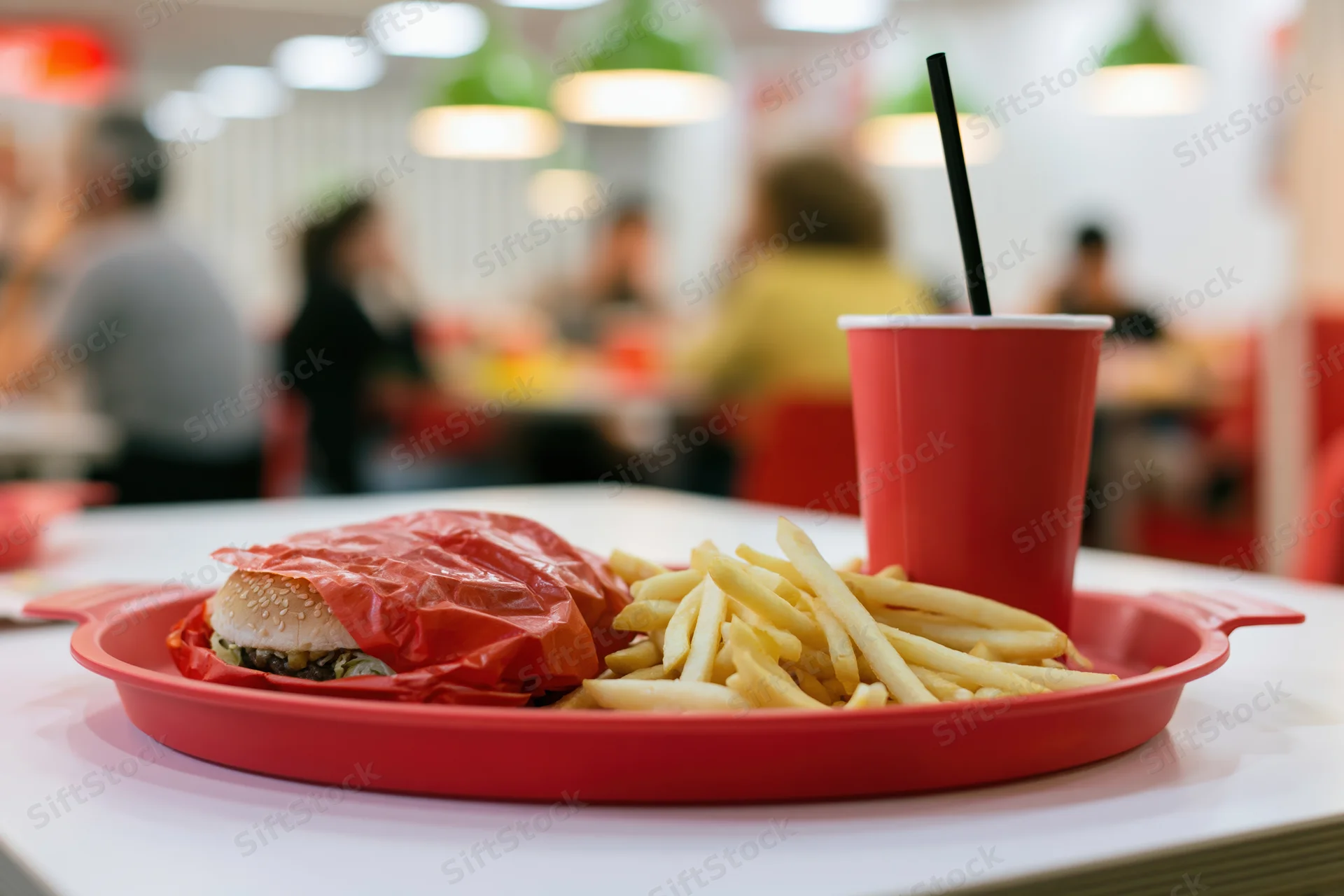 Red tray with wrapped burger and fries on a table in a fast food restaurant