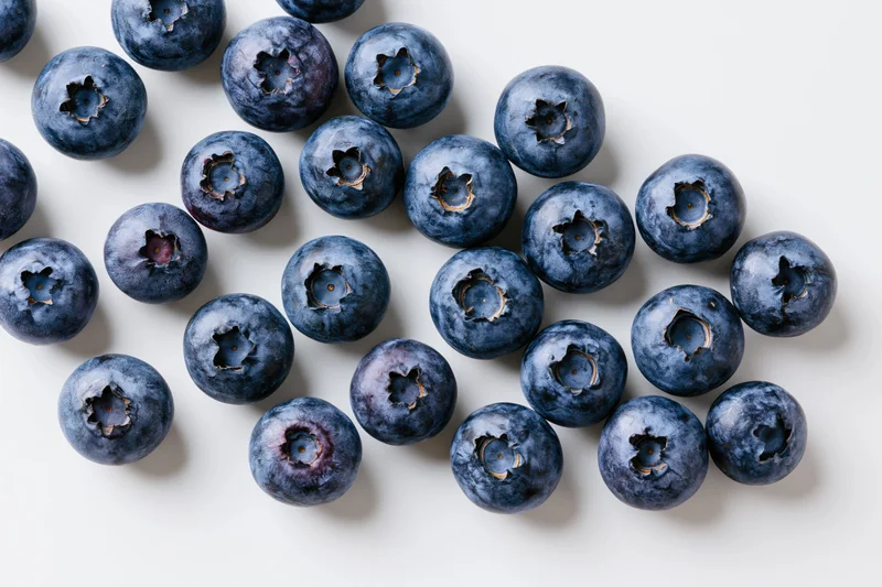 Fresh blueberries scattered across a white surface in a flat lay arrangement