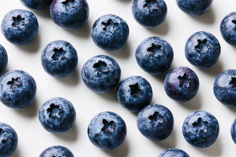 Fresh blueberries scattered across a white surface in a flat lay top view