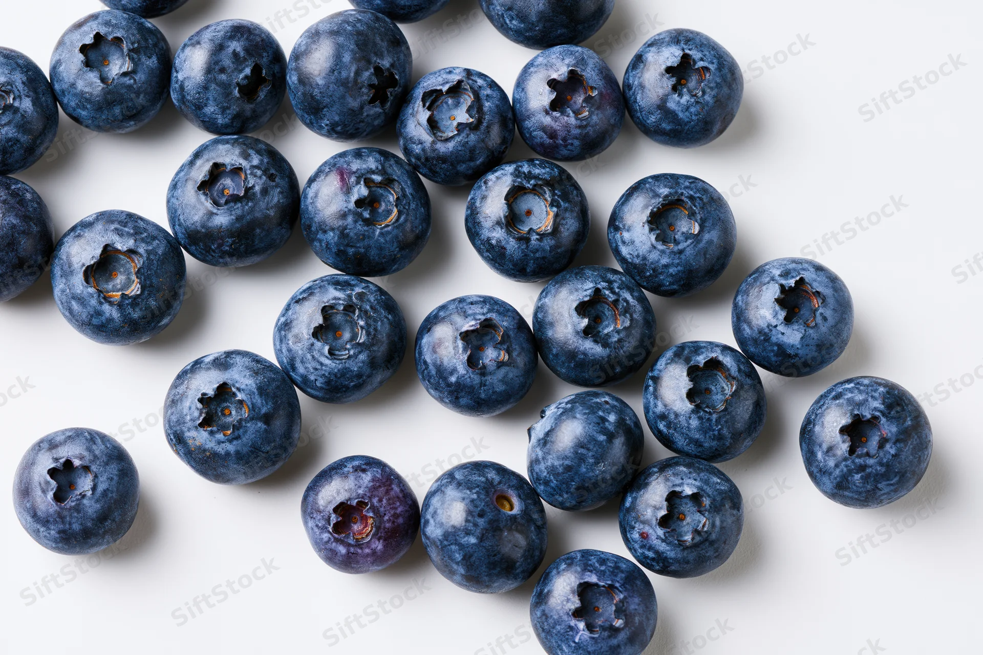Fresh blueberries scattered on white background in closeup top view