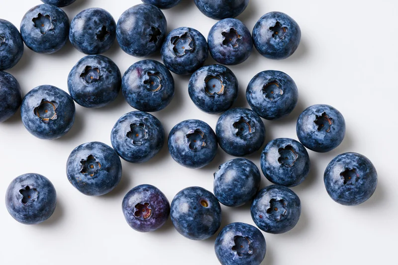 Fresh blueberries scattered on white background in closeup top view